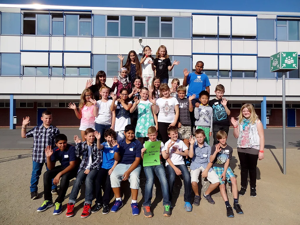 Klassenfoto einer neuen fünften Klasse, die Kinder jubeln.